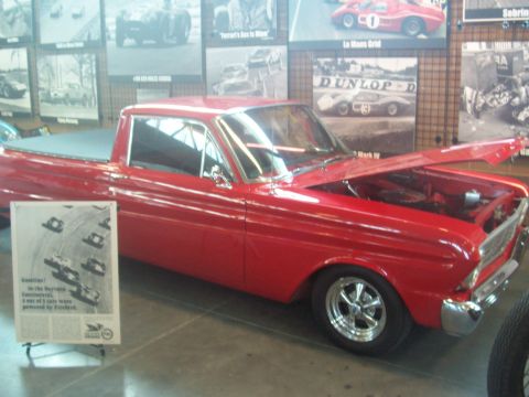 1972 Ford Ranchero - A red 1964 Ford Falcon Ranchero is displayed indoors, with racing photographs on the wall behind it.