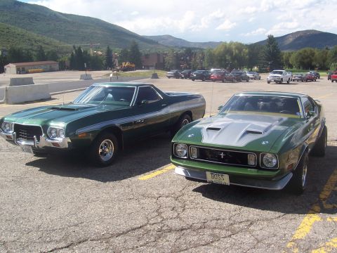 1972 Ford Ranchero - Two classic American muscle cars, a Ford Ranchero and a Ford Mustang, are parked side-by-side in a lot.