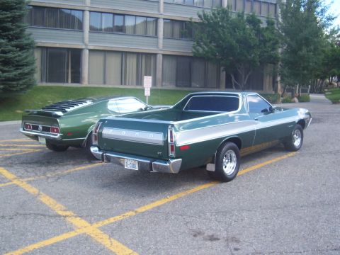 1972 Ford Ranchero - A green 1972 Ford Ranchero GT is parked next to another green vehicle, showing its rear end and distinctive Q-CODE license plate.