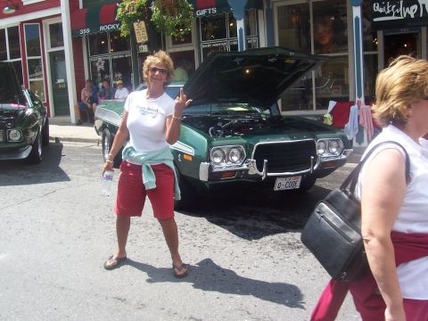1972 Ford Ranchero - A woman poses with a vintage green muscle car, which appears to be a 1970 model, not a 1972 Ford Ranchero.