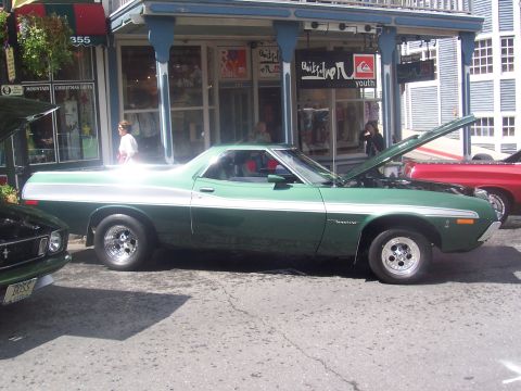 1972 Ford Ranchero - A green 1972 Ford Ranchero with a white stripe and hood open is parked on a street.