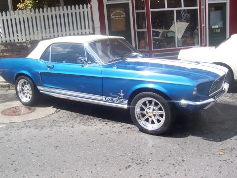 1972 Ford Ranchero - A blue 1968 Ford Mustang GT 500 convertible is parked in front of a shop with a white picket fence.