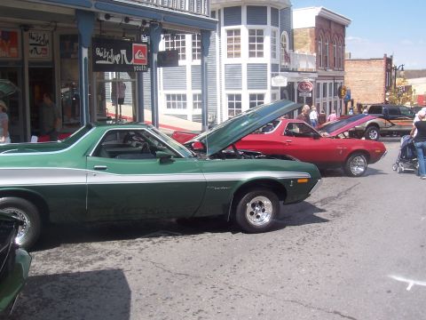 1972 Ford Ranchero - Two Ford Rancheros, a green one in the foreground and a red one behind it, are parked on a street with their hoods open.