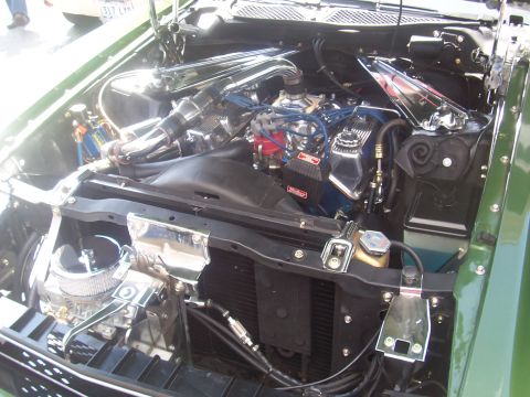 1972 Ford Ranchero - The engine bay of a green vehicle is shown with custom chrome parts and blue wiring.