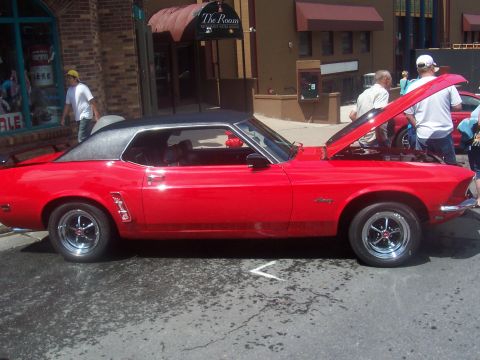 1972 Ford Ranchero - A red coupe with a black vinyl top and chrome wheels is parked on a street with its hood open.