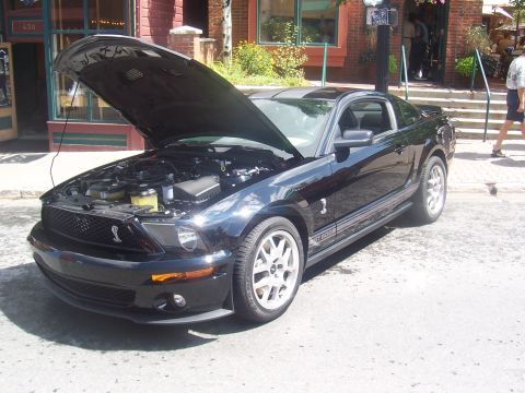 1972 Ford Ranchero - Black Ford Mustang Shelby GT500 parked on street with hood open, revealing the engine compartment.