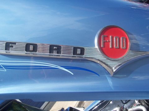 1972 Ford Ranchero - The hood of a blue vehicle displays the Ford F-100 emblem and custom pinstriping.