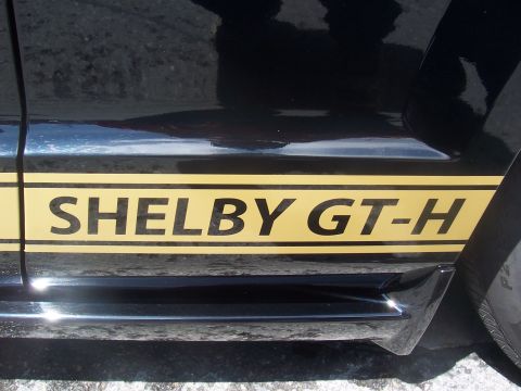 1972 Ford Ranchero - A black car displays a gold Shelby GT-H stripe along its side panel.