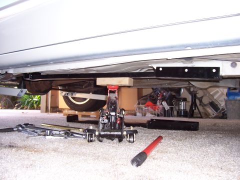 1978 Ford Mustang II - The underside of a white vehicle is visible, supported by a jack and various tools.