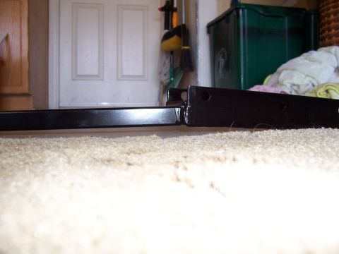 1978 Ford Mustang II - A black metal bracket is shown on a carpeted surface, with household items in the background.