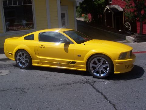 1972 Ford Ranchero - Yellow Ford Mustang parked on a street with buildings in the background.
