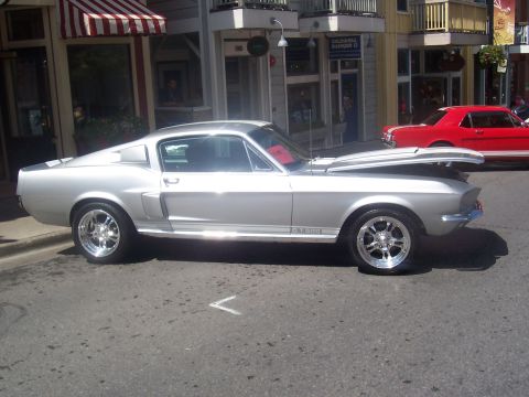 1972 Ford Ranchero - A silver 1967 Ford Mustang GT500 is parked on a street with its hood open, next to a red car.