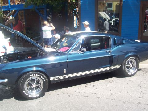 1972 Ford Ranchero - A blue 1967 Shelby GT500 is displayed with its hood open, white racing stripes along its body.