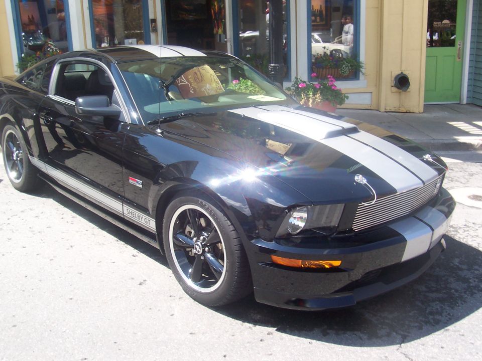 Black Ford Mustang Shelby GT with silver racing stripes parked on a street