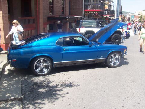 1972 Ford Ranchero - A blue 1970 Ford Mustang is displayed on a street with its hood open, alongside other vehicles.