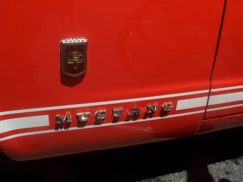 1972 Ford Ranchero - A red car's side panel displays a GT emblem and the word MUSTANG in chrome lettering.