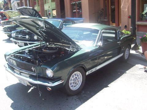 1972 Ford Ranchero - A dark green 1967 Ford Mustang GT350 is displayed with its hood open, parked alongside other vehicles.