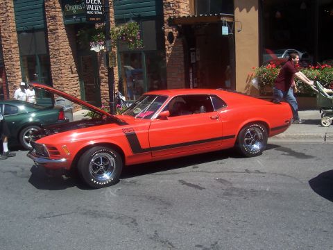 1972 Ford Ranchero - A red muscle car with its hood open is parked on a street, with a green car visible behind it.