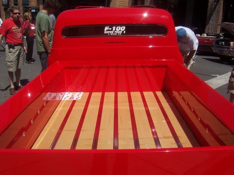 1972 Ford Ranchero - A red pickup truck bed with a wooden floor is shown, with a sticker on the rear window.