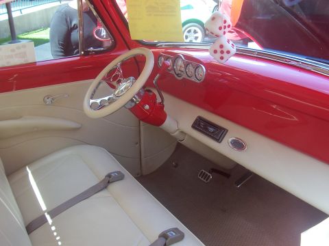 1972 Ford Ranchero - The interior of a classic car features a red dashboard, cream upholstery, and a white steering wheel with fuzzy dice hanging from the mirro…