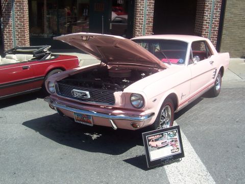 1972 Ford Ranchero - A pink 1965 Ford Mustang is displayed with its hood up, alongside another convertible.