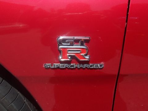 1972 Ford Ranchero - Close-up of a red car fender displaying the 'GT-R Supercharged' emblem.