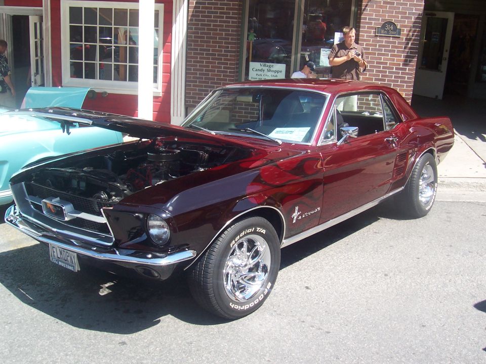 1967 Ford Mustang coupe with hood open, parked next to a light blue car