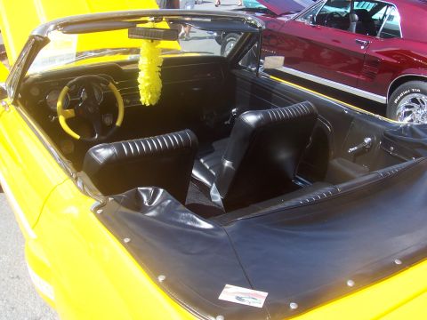 1972 Ford Ranchero - A yellow 1967 Ford Mustang convertible interior is shown, with a red car visible in the background.