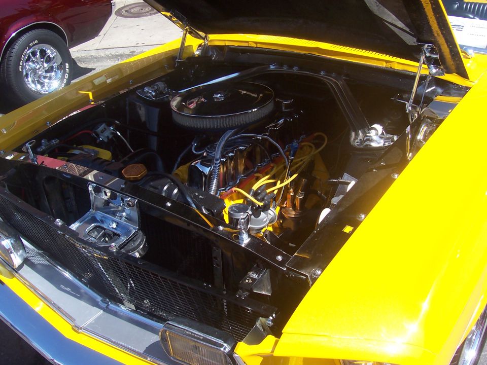 Yellow car engine bay with chrome accents and V8 engine