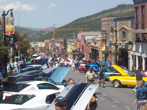 1972 Ford Ranchero - A street is filled with parked cars and spectators during a sunny day event.