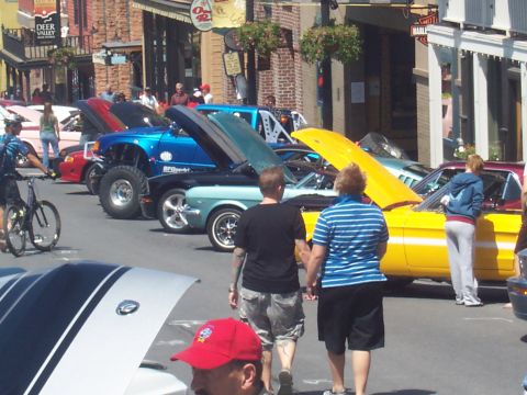 1972 Ford Ranchero - A bright yellow classic car is displayed with its hood open at an outdoor car show.