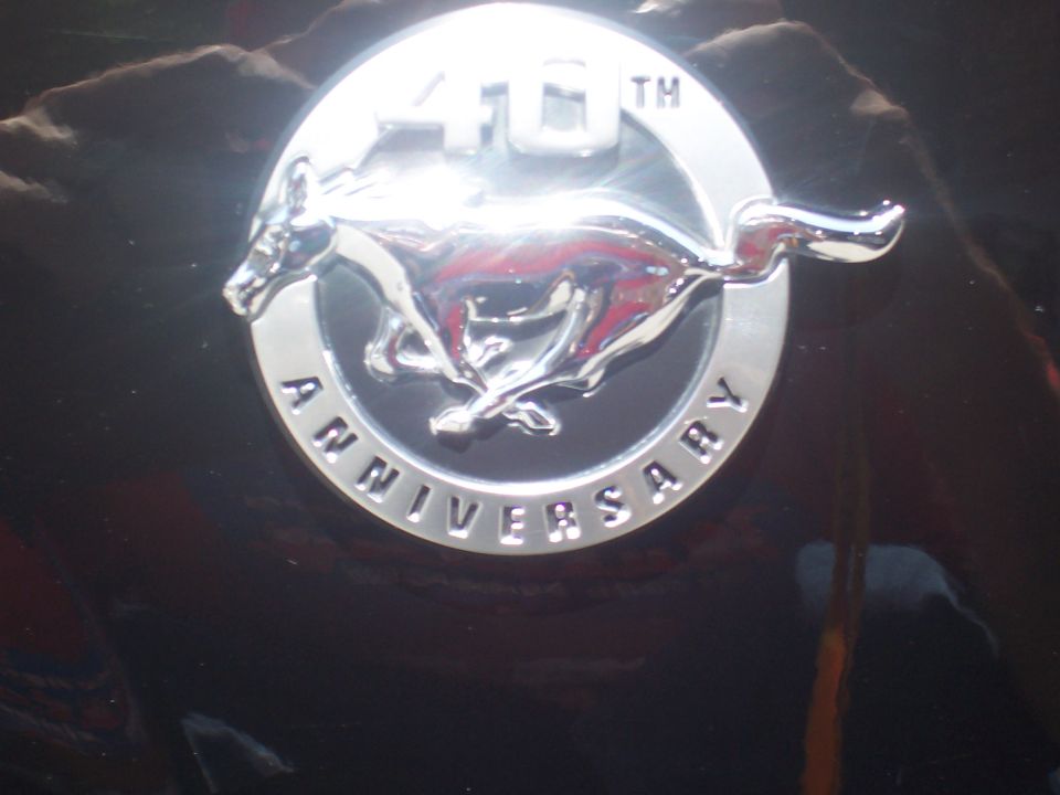 Close-up of a chrome 40th Anniversary emblem with a running horse on a black surface