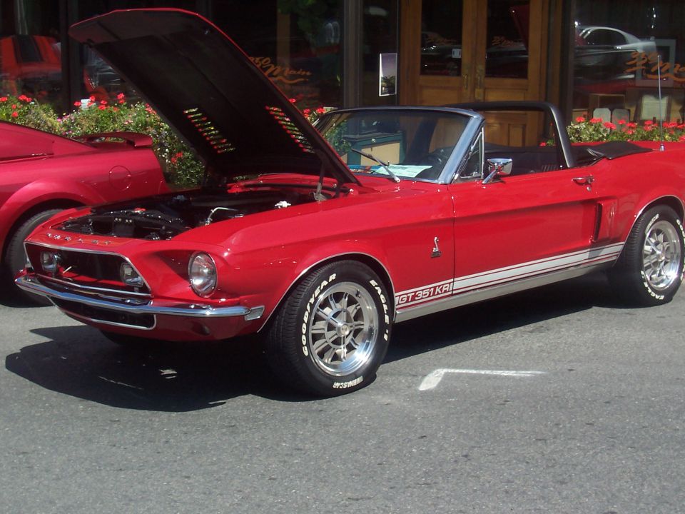 Red convertible with white racing stripes and "GT 351 KRI" text, hood open revealing engine