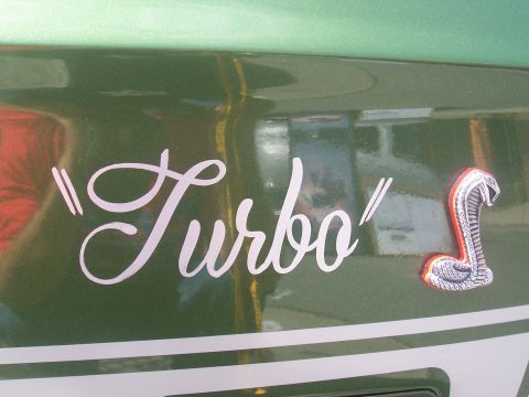 1972 Ford Ranchero - Detail of a green vehicle 'Turbo' badging and a cobra emblem on its side.