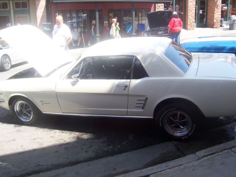 1972 Ford Ranchero - A white 1965 Ford Mustang is parked on the street with its hood open, alongside other vehicles.