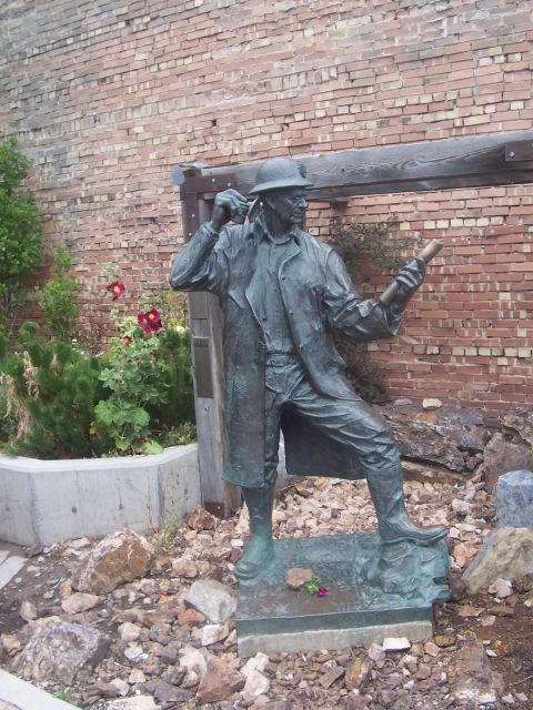 1972 Ford Ranchero - Outdoor bronze statue depicts a man in period attire holding a scroll against a brick wall.
