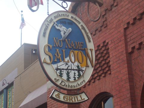 1972 Ford Ranchero - A sign for the No Name Saloon & Grill hangs in front of a brick building.