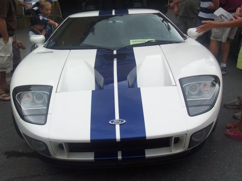 1972 Ford Ranchero - A white Ford GT with blue racing stripes is displayed from the front, with onlookers gathered around.