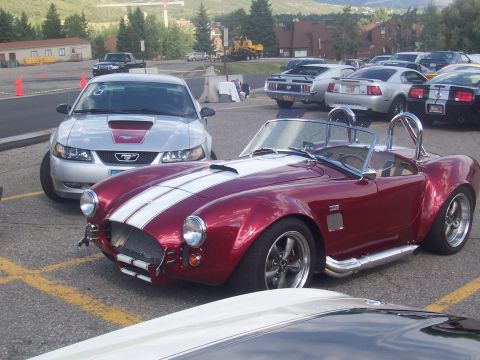 1972 Ford Ranchero - A classic red convertible with dual white racing stripes is parked in a lot alongside other vehicles.