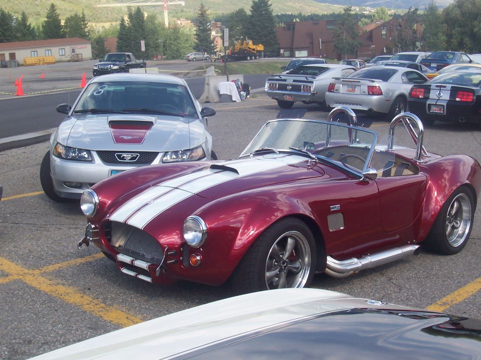 Red convertible with white stripes, front view, parked with other cars