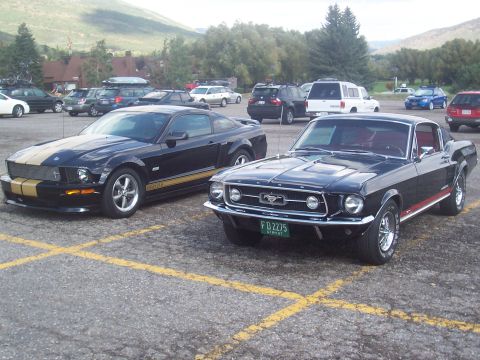 1972 Ford Ranchero - A classic 1968 Ford Mustang is parked next to a more contemporary model in a parking lot, with mountains in the background.