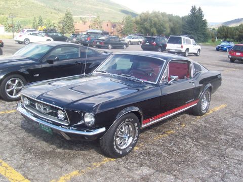 1972 Ford Ranchero - Black 1967 Ford Mustang Fastback parked in a lot with other vehicles.