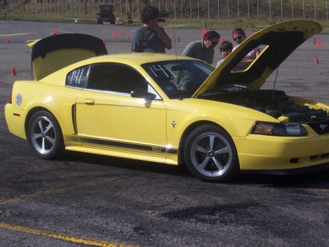1972 Ford Ranchero - A yellow Ford Mustang coupe sits with its hood and trunk open, revealing the engine and interior.