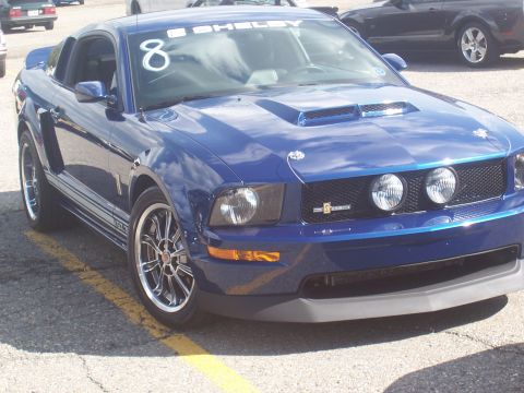 1972 Ford Ranchero - A blue Shelby Mustang with racing stripes and the number 8 displayed on the windshield is parked on asphalt.