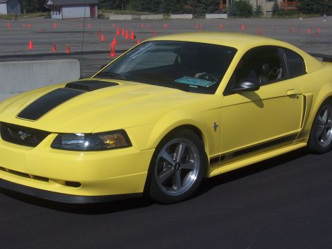 1972 Ford Ranchero - A yellow Ford Mustang is parked on an asphalt surface, with orange cones visible in the background.