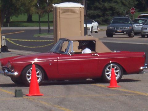 1972 Ford Ranchero - Side view of a red convertible sports car with tan top and silver wheels.