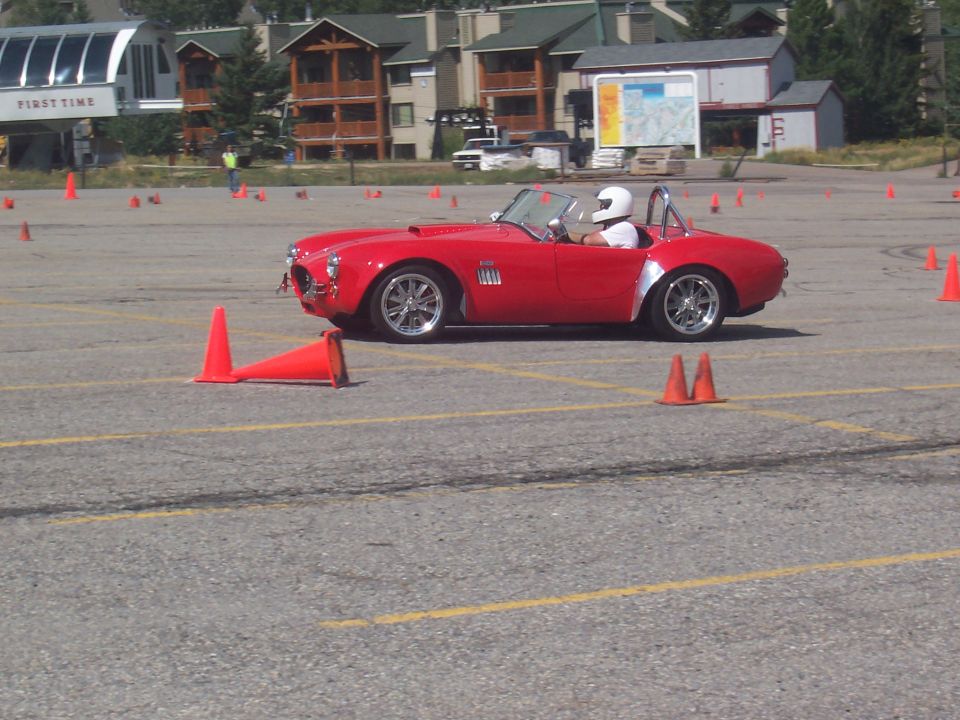 Red convertible sports car navigating a cone course
