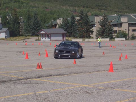 1972 Ford Ranchero - A dark gray coupe with racing number 15 drives through an autocross course with cones and buildings in the background.