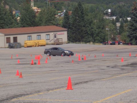 1972 Ford Ranchero - A gray coupe is seen maneuvering through an autocross course with numerous orange cones set up on the asphalt.