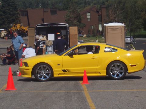 1972 Ford Ranchero - Yellow Ford Mustang parked on asphalt with cones and a trailer in the background.